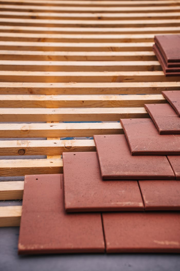 gallery-1 Red roofing tiles and wooden framework in progress on a building roof.