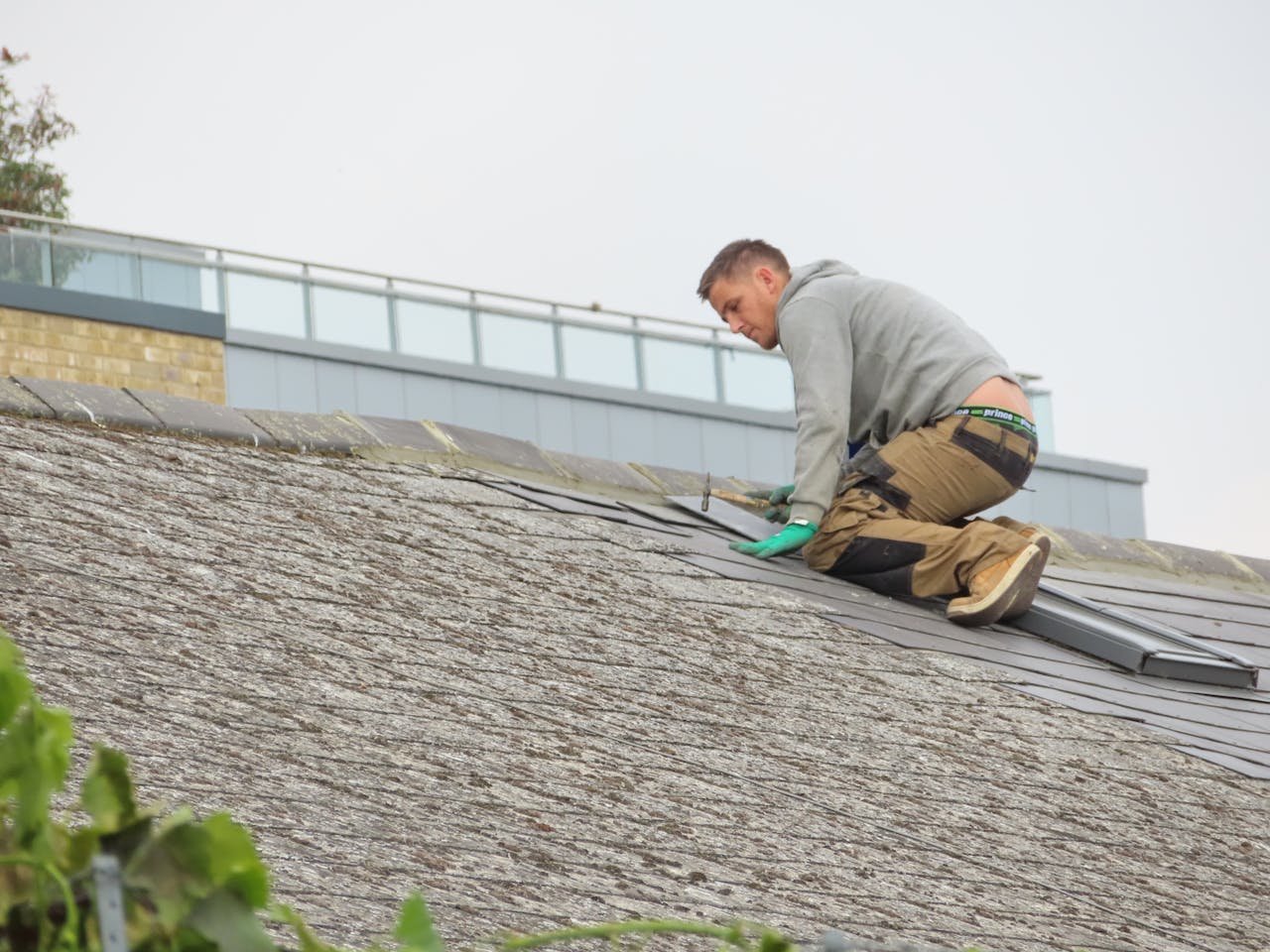 hero-img-01 Construction worker installing shingles on a rooftop. Outdoor building maintenance.